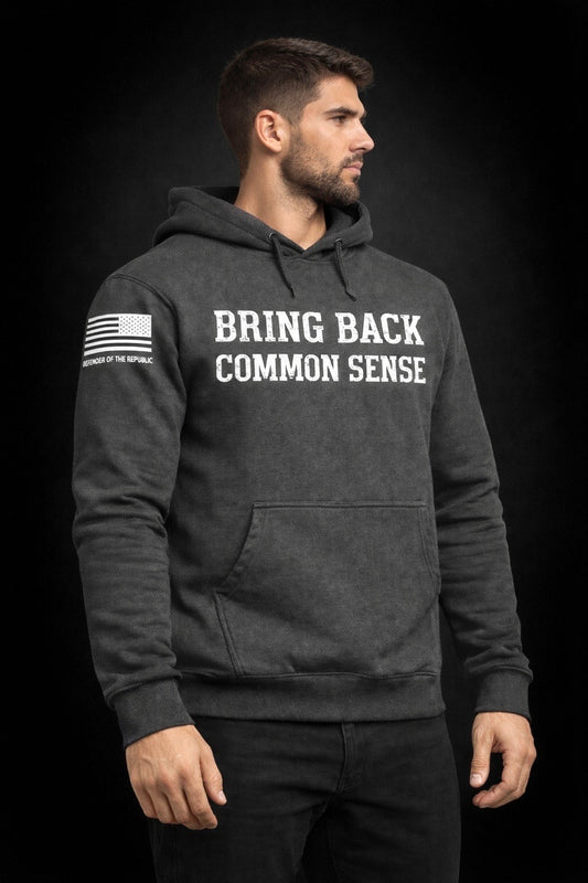 Man wearing a gray hoodie with 'Bring Back Common Sense' white text on the front and a white American flag on right sleeve with small text reading Defender of the Republic' - entire picture on a black background