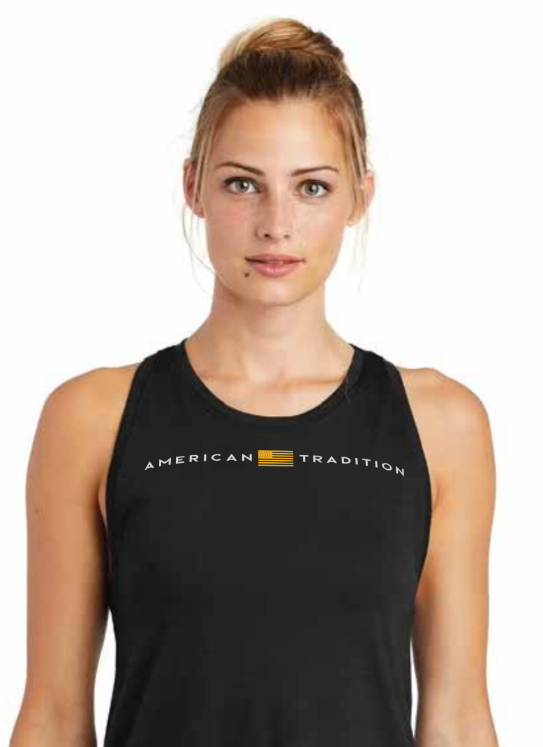 A woman wearing a black sleeveless tank top with 'AMERICAN TRADITION' printed in white across the chest, separated by a small gold American flag graphic.